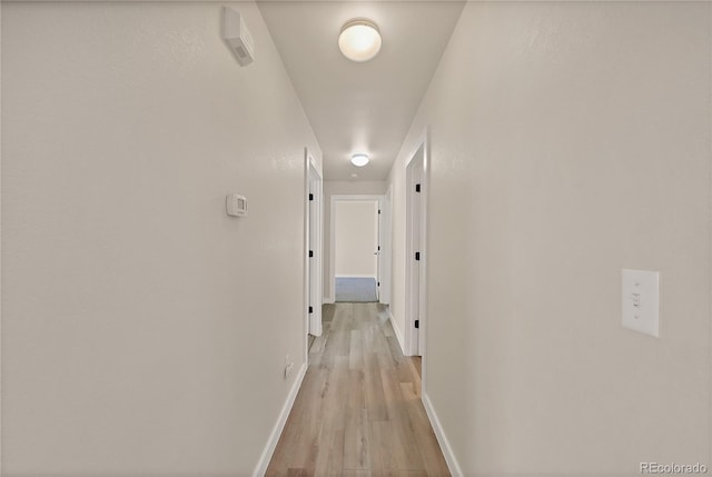 hall featuring baseboards and light wood-style flooring