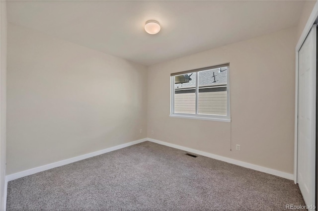 spare room featuring baseboards, visible vents, and carpet