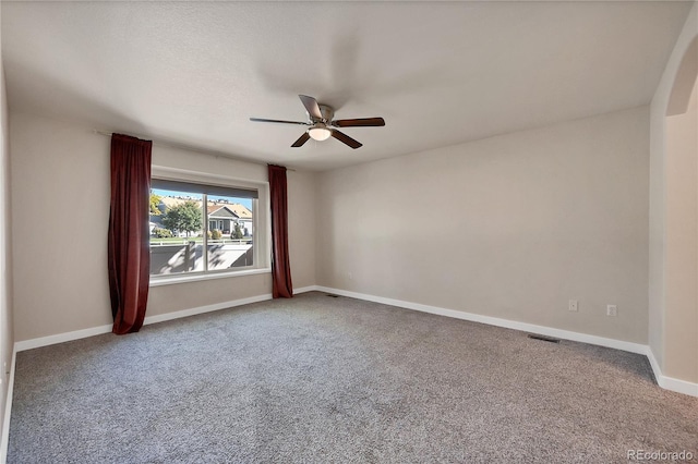 empty room with baseboards, visible vents, ceiling fan, and carpet