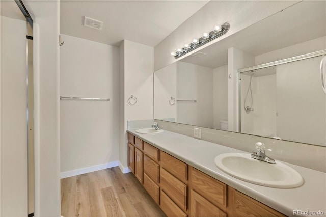 bathroom with wood-type flooring, vanity, toilet, and a shower with shower door