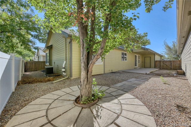 rear view of property featuring a fenced backyard, central AC, and a patio area