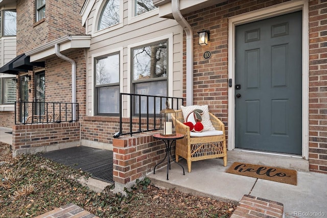 view of exterior entry with brick siding and covered porch