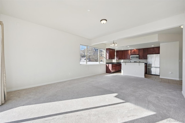 unfurnished living room featuring a chandelier and light colored carpet