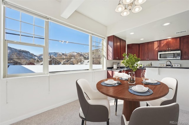 carpeted dining room with beamed ceiling, a mountain view, and a chandelier