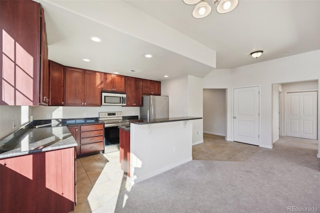 kitchen featuring a breakfast bar, a center island, dark stone countertops, light colored carpet, and stainless steel appliances