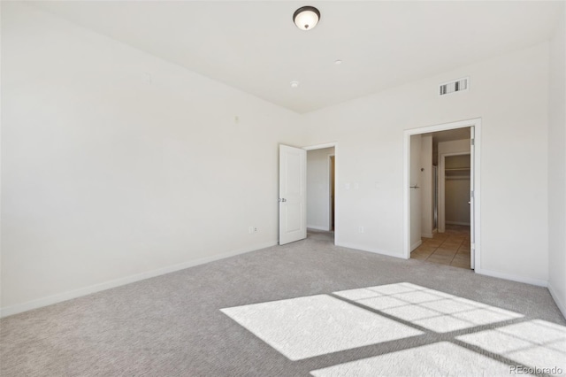 unfurnished bedroom featuring light colored carpet, a spacious closet, and a closet