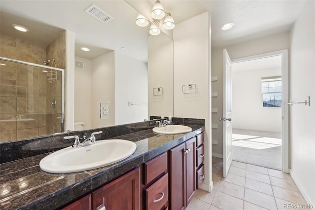 bathroom featuring tile patterned flooring, vanity, toilet, and an enclosed shower