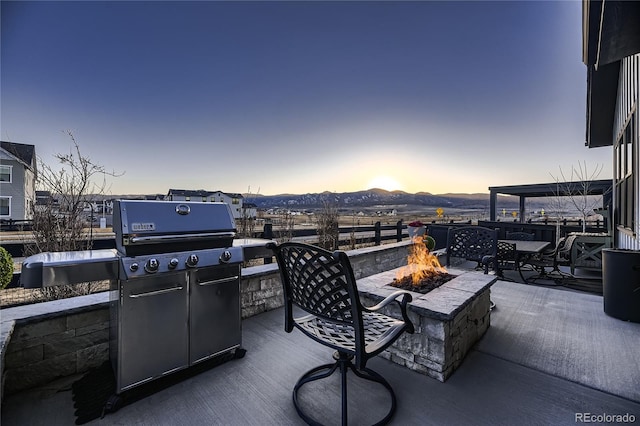 patio terrace at dusk featuring an outdoor fire pit and a mountain view