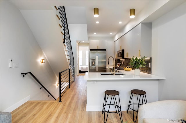 kitchen featuring kitchen peninsula, a kitchen breakfast bar, sink, white cabinets, and stainless steel appliances