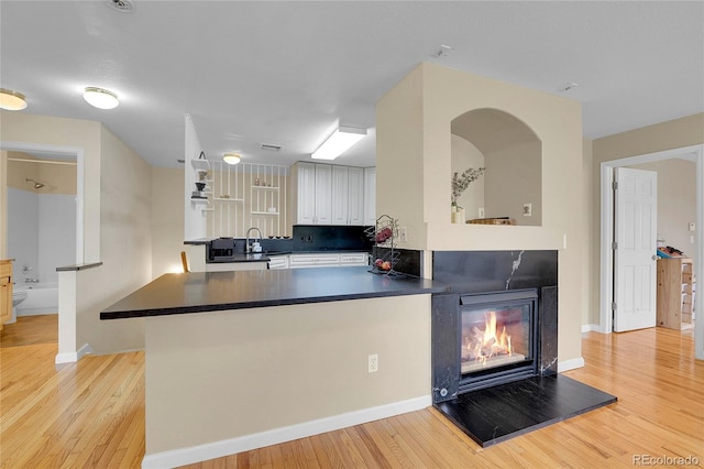 1308 S Danube Way Unit 102, Aurora, CO 80017 - kitchen featuring light wood-type flooring, baseboards, and white cabinetry