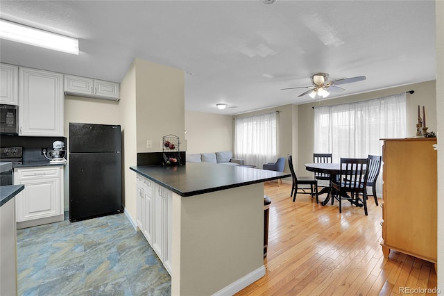 1308 S Danube Way Unit 102, Aurora, CO 80017 - kitchen with black appliances, dark countertops, a peninsula, white cabinets, and a ceiling fan