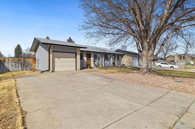 view of front of property with a garage, brick siding, concrete driveway, and fence