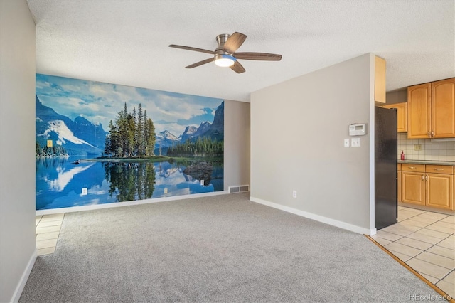 unfurnished living room with visible vents, baseboards, ceiling fan, light colored carpet, and a textured ceiling