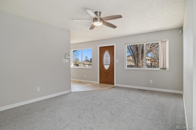 carpeted entryway featuring baseboards, visible vents, a textured ceiling, and ceiling fan