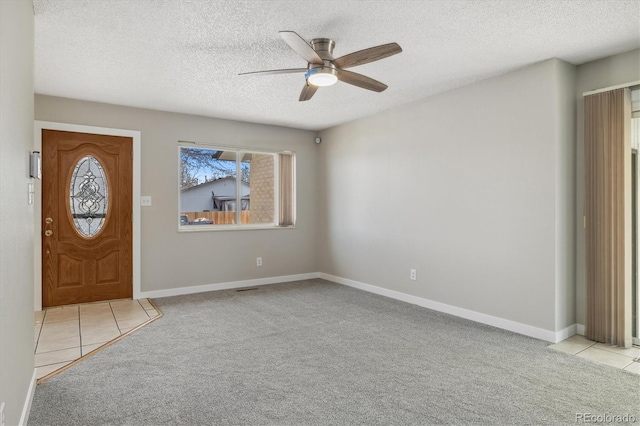 carpeted foyer featuring baseboards, tile patterned floors, a textured ceiling, and a ceiling fan