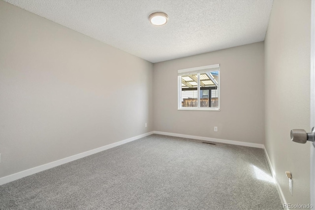 unfurnished room featuring visible vents, a textured ceiling, baseboards, and carpet