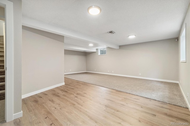 basement featuring visible vents, baseboards, wood finished floors, and stairs