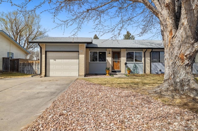 single story home featuring a garage, brick siding, concrete driveway, and fence