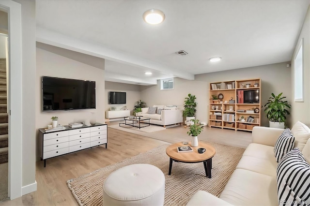 living room featuring visible vents, plenty of natural light, stairway, and wood finished floors
