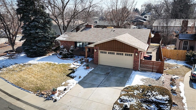 ranch-style house with brick siding, concrete driveway, an attached garage, board and batten siding, and fence