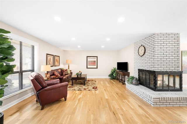 living area with baseboards, recessed lighting, a fireplace, and light wood-style floors