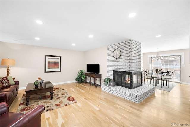 living area with a brick fireplace, baseboards, light wood-style floors, a chandelier, and recessed lighting