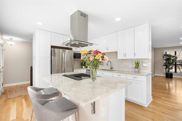 kitchen with white cabinets, a kitchen island, freestanding refrigerator, and island range hood