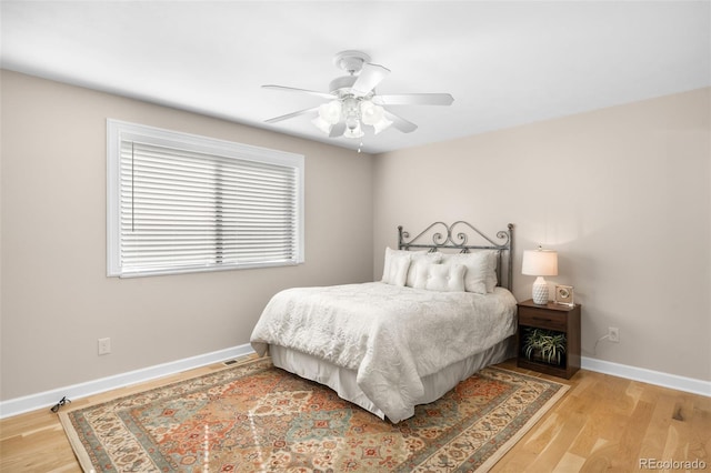 bedroom with baseboards, a ceiling fan, and light wood-style floors