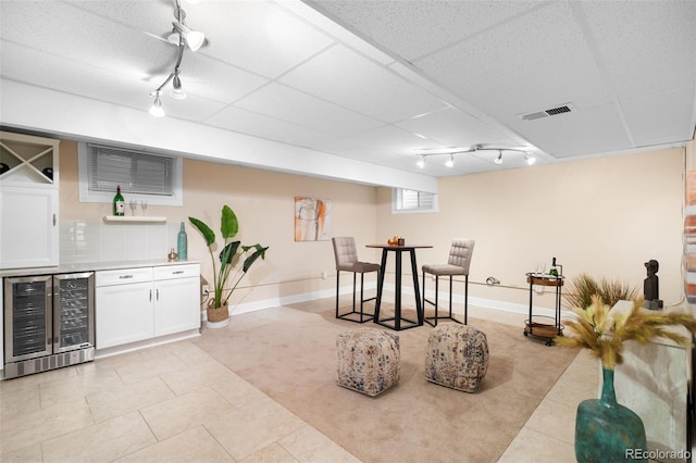 bar with a dry bar, beverage cooler, visible vents, a drop ceiling, and track lighting