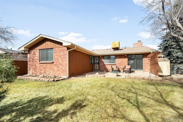 back of property with a patio, brick siding, a lawn, and fence