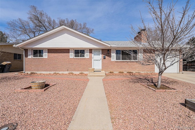 single story home with an attached garage, brick siding, a chimney, and driveway