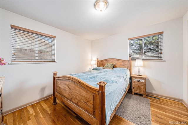 bedroom with multiple windows, baseboards, and light wood-style floors