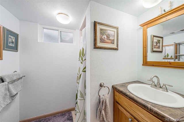 bathroom featuring a shower with shower curtain, visible vents, vanity, and a textured wall