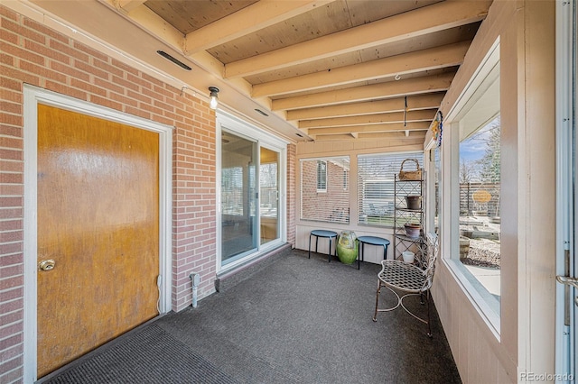 unfurnished sunroom featuring beam ceiling