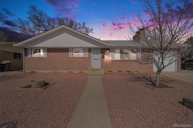 single story home with brick siding, a garage, driveway, and a chimney