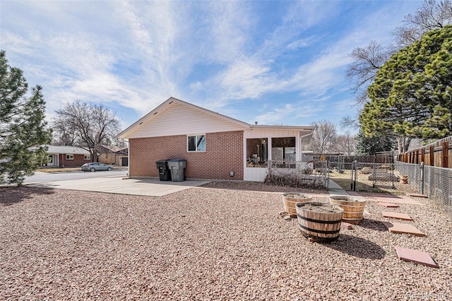 back of house with a patio area, fence, and brick siding