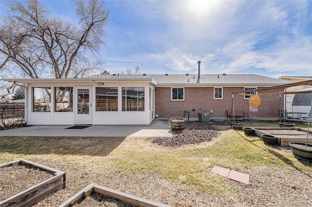 back of house featuring brick siding, a patio area, and a vegetable garden