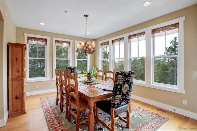 dining space with light hardwood / wood-style flooring and a chandelier