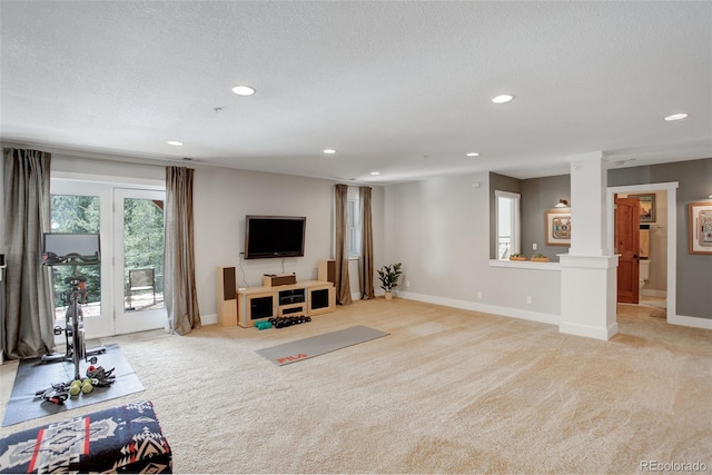 living room featuring decorative columns, light colored carpet, and a textured ceiling