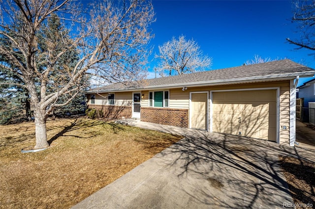 ranch-style home with a front yard, concrete driveway, brick siding, and an attached garage