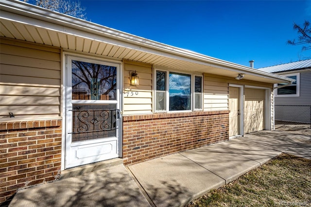 property entrance with brick siding and an attached garage