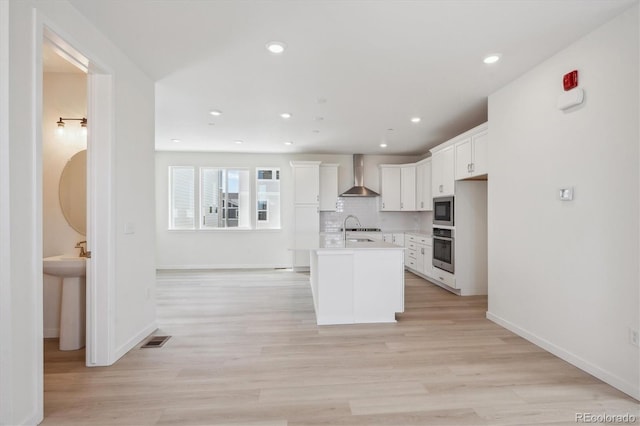 1257 Rhett Dr, Erie, CO 80026 - kitchen with appliances with stainless steel finishes, wall chimney range hood, white cabinetry, light countertops, and a center island with sink