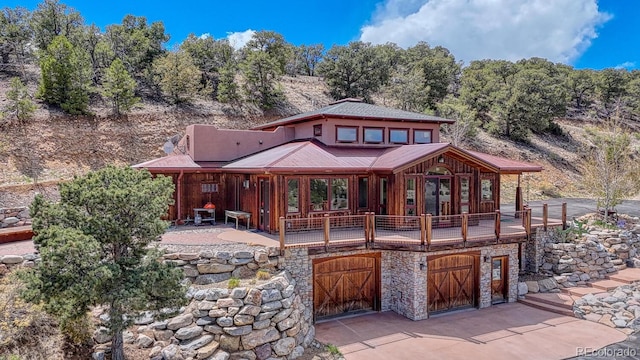 12220 Saddle Ridge Ln, Salida, CO 81201 - rear view of property featuring an attached garage, stone siding, and driveway