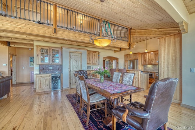 12220 Saddle Ridge Ln, Salida, CO 81201 - dining area featuring wine cooler, arched walkways, light wood-style flooring, beamed ceiling, and wood ceiling