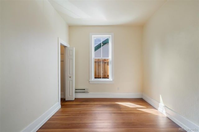 unfurnished room featuring hardwood / wood-style floors and baseboard heating