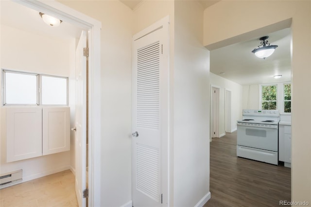 corridor with hardwood / wood-style floors and a baseboard heating unit