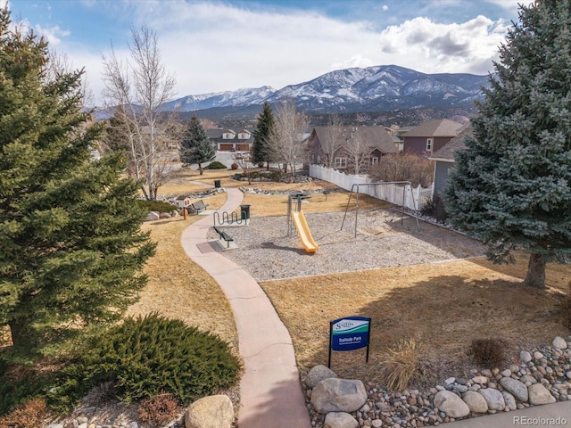 view of community with playground community, fence, and a mountain view