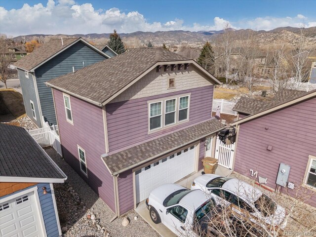 view of front of property with a garage, fence, a mountain view, and roof with shingles