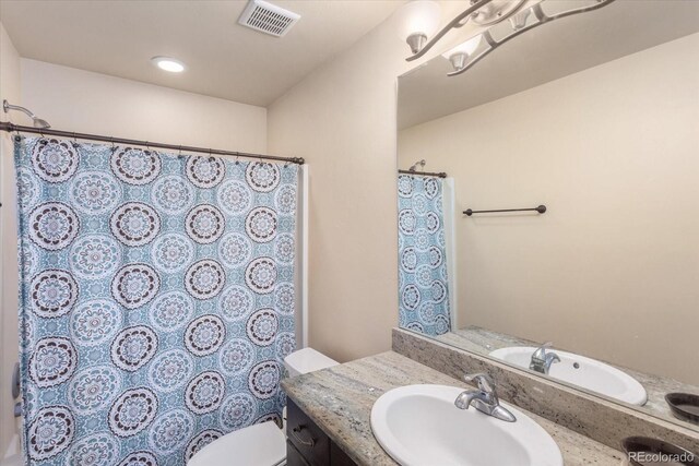 bathroom with toilet, vanity, visible vents, and a shower with curtain