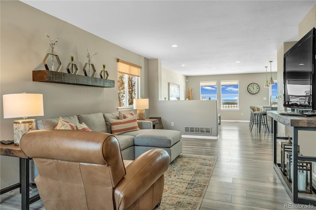 living room featuring baseboards, recessed lighting, wood finished floors, and visible vents